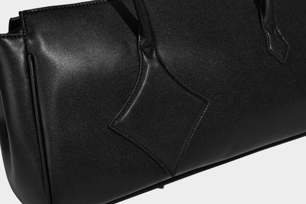 Strukturierte Tote-Bag in schwarzer Lederoptik mit Drehverschluss in Vorhängeschloss-Optik, dekorativen Riemendetails und abgerundeten Doppelhenkeln