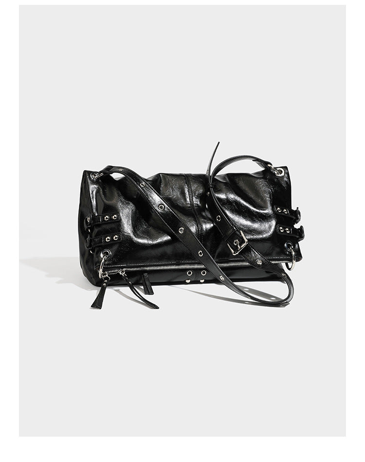 Black glossy leather-look slouchy shoulder bag with silver stud and eyelet hardware, top zip closure, front zip pocket, and