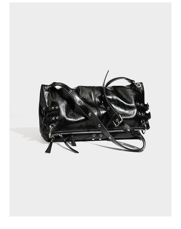 Black glossy leather-look slouchy shoulder bag with silver stud and eyelet hardware, top zip closure, front zip pocket, and