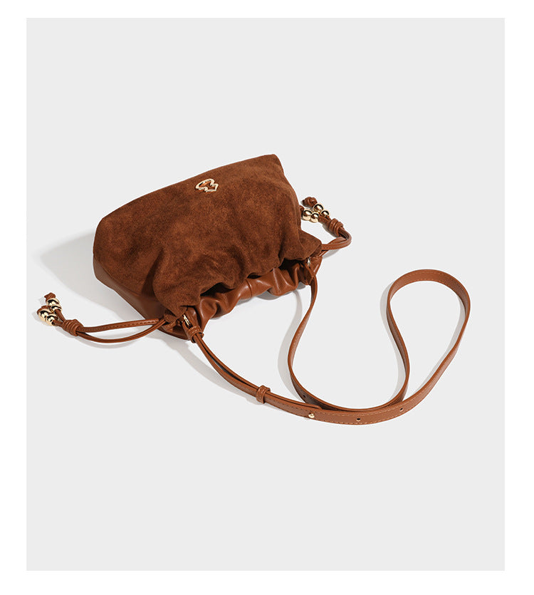 Suede-look drawstring shoulder bag in brown with smooth trim, knotted bead drawstring closure, slim adjustable strap, and