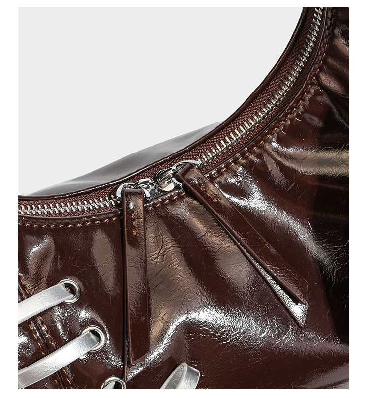 Lässige Hobo-Schultertasche in glänzender Lederoptik mit silbernen Schnürösen und einer Schleife aus Ripsband auf der Vorderseite, Detail