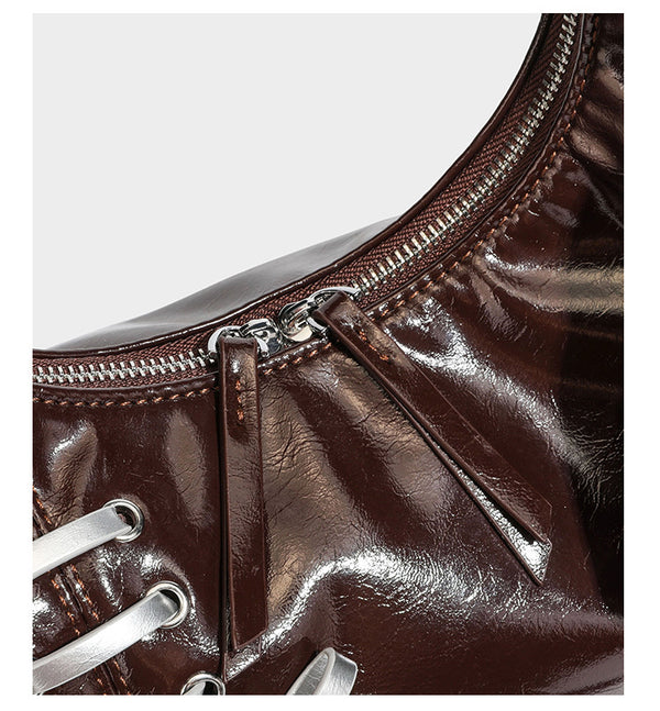 Lässige Hobo-Schultertasche in glänzender Lederoptik mit silbernen Schnürösen und einer Schleife aus Ripsband auf der Vorderseite, Detail