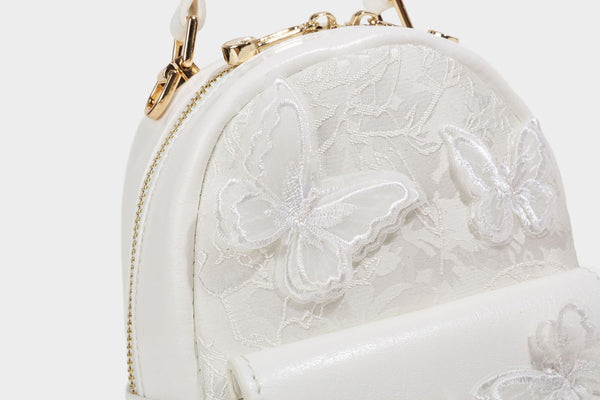 Structured mini backpack handbag with butterfly embroidery, gold-tone chain strap, and turn-lock front flap pocket, detail