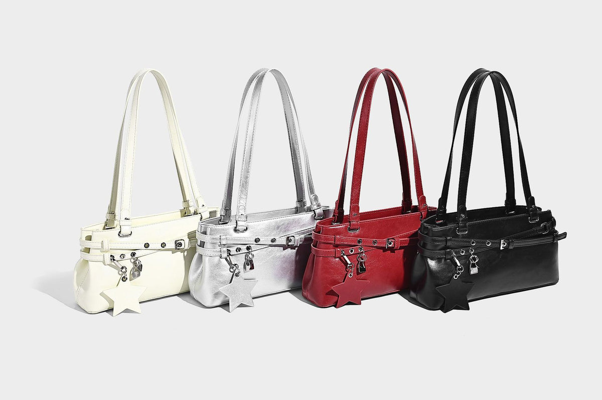 Structured glossy leather-look shoulder bag with wraparound belt straps, silver-tone hardware, and dangling star charm