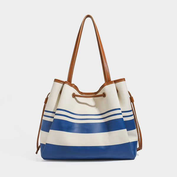Large cream and navy striped canvas bucket tote bag with tan leather-look trim, drawstring closure, and double shoulder