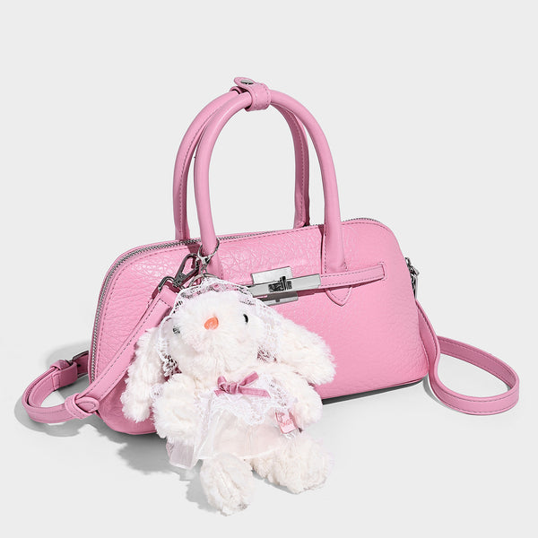 Small structured shell-silhouette top-handle bag with pebbled leather-look finish, silver-tone turn-lock hardware, and, front