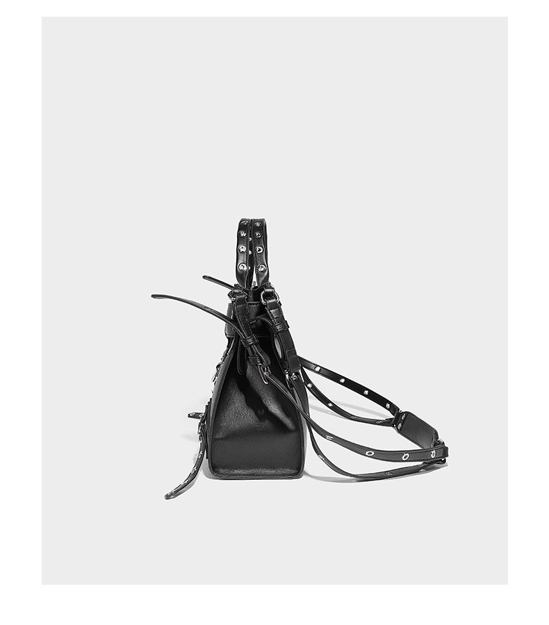 Black structured rectangular satchel bag with silver-tone rivets, large front buckle strap, zip pockets, dual top handles