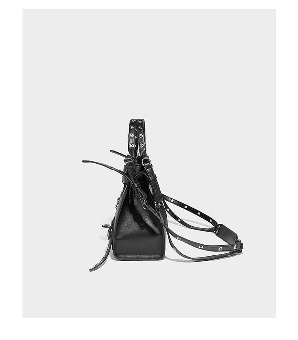 Black structured rectangular satchel bag with silver-tone rivets, large front buckle strap, zip pockets, dual top handles