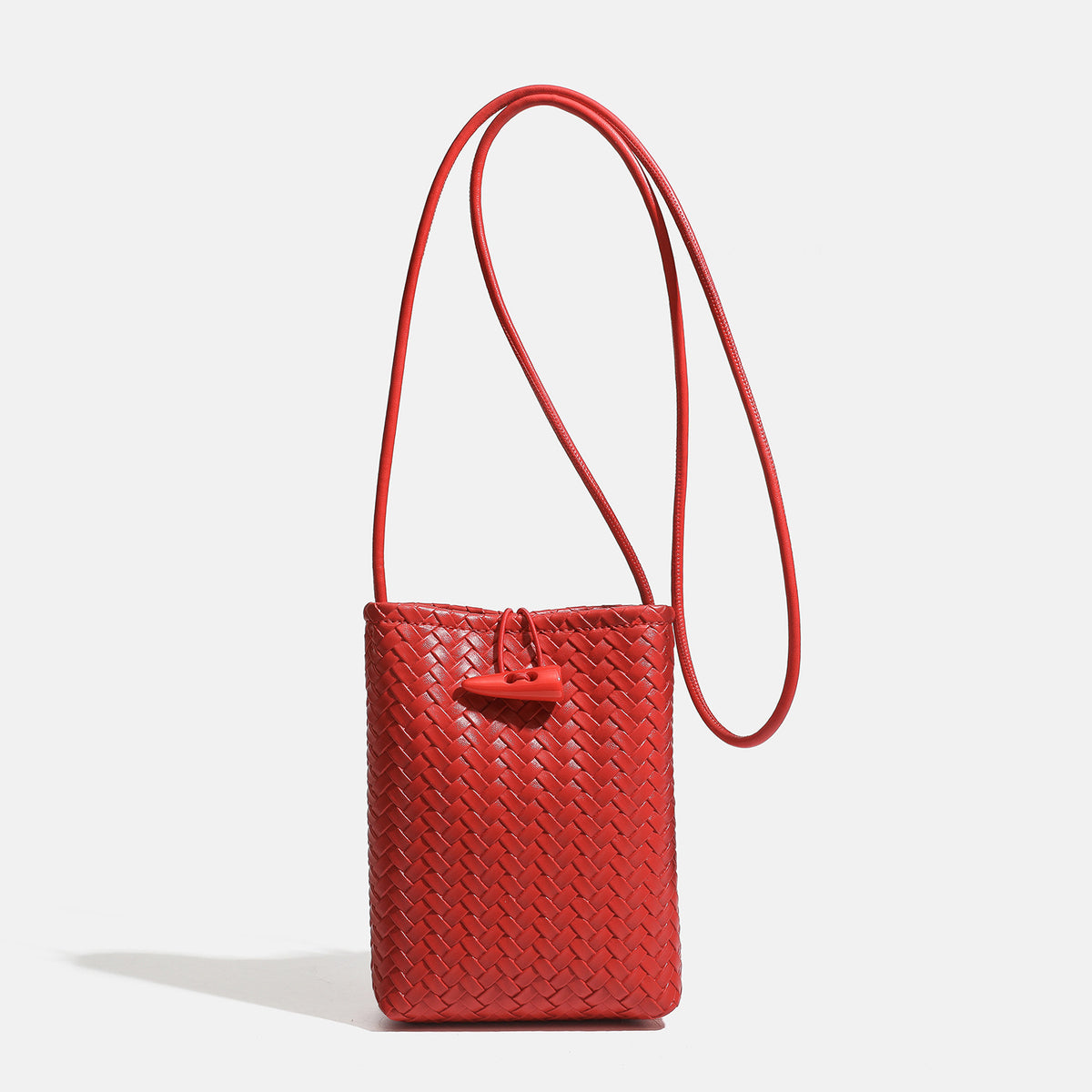 Compact woven leather-look bucket crossbody pouch with toggle closure and long fixed strap, front view