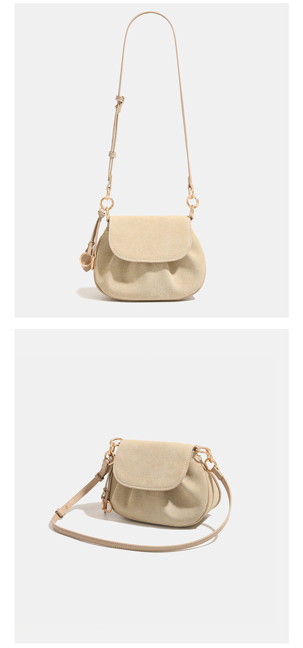 Small rounded flap crossbody saddle bag with gold-tone ring hardware and adjustable strap, detail view 9