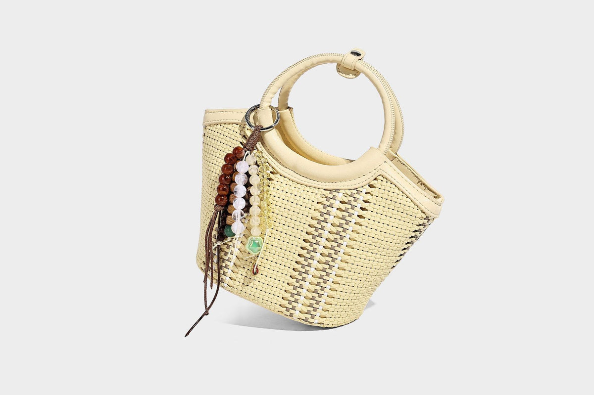 Kleine strukturierte Beuteltasche aus geflochtenem Material mit rundem Tragegriff in Lederoptik, silberfarbenen Beschlägen und perlenbesetztem Quastenanhänger, Detail