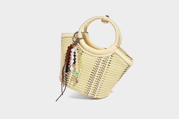 Kleine strukturierte Beuteltasche aus geflochtenem Material mit rundem Tragegriff in Lederoptik, silberfarbenen Beschlägen und perlenbesetztem Quastenanhänger, Detail