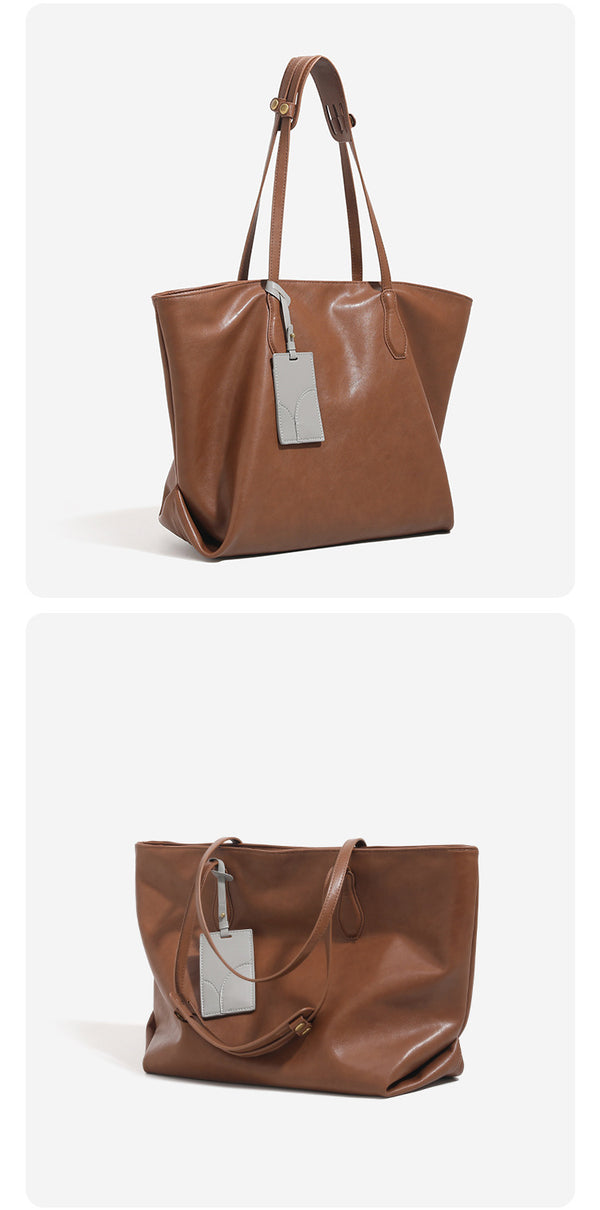 Oversized slouchy leather-look tote bag with long shoulder straps, contrast grey hanging tag, and silver-tone hardware