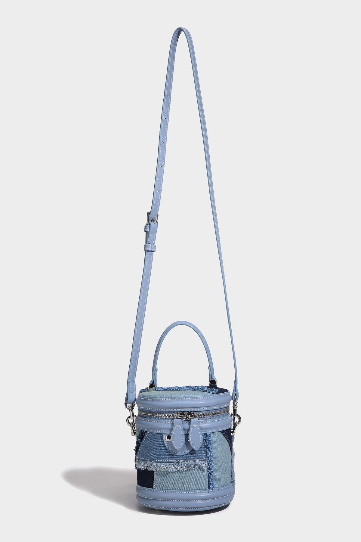 Mini cylindrical barrel bucket bag in denim patchwork with frayed edges, smooth leather-look trim, zip-around top closure