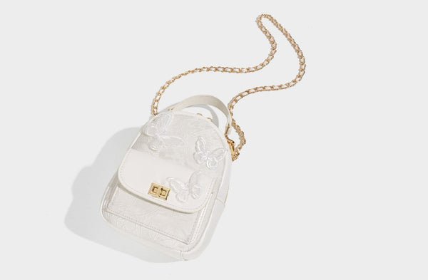 Structured mini backpack handbag with butterfly embroidery, gold-tone chain strap, and turn-lock front flap pocket, detail
