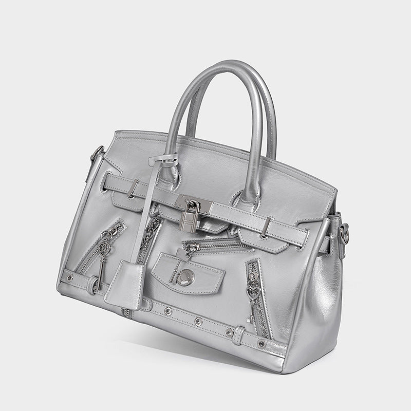Structured black leather-look satchel bag with silver padlock hardware, front zip pockets, key charms, and top handles