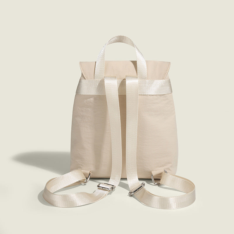 Soft matte nylon drawstring backpack with ruched bow-detail front zip pockets, top carry handle, and silver-tone hardware