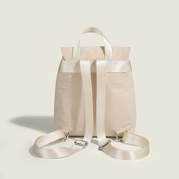 Soft matte nylon drawstring backpack with ruched bow-detail front zip pockets, top carry handle, and silver-tone hardware