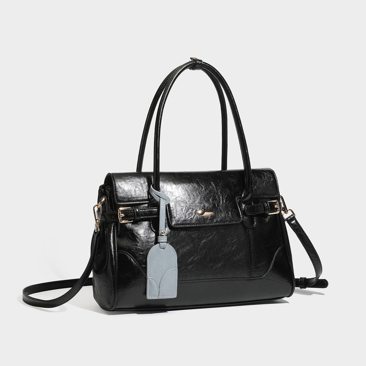 Structured glossy leather-look satchel bag with flap closure, gold-tone buckle accents, double top handles, detachable