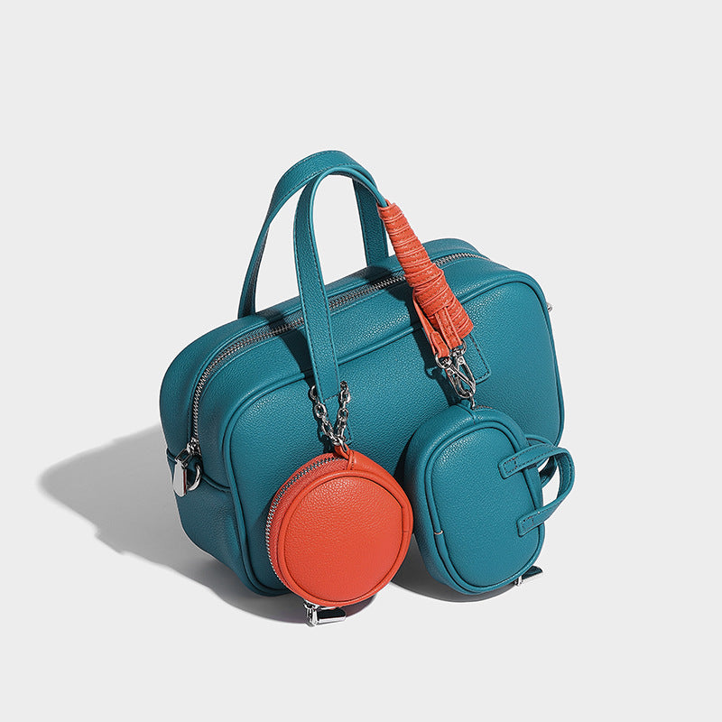 Structured pebbled leather-look Boston bowling bag in tan with blue detachable round mini pouch, dual top handles, and