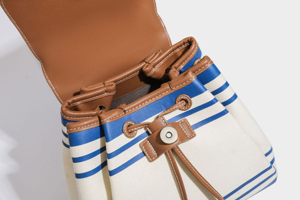 Cream canvas bucket bag with blue horizontal stripes, tan leather-look flap and trim, drawstring closure, silver-tone, detail