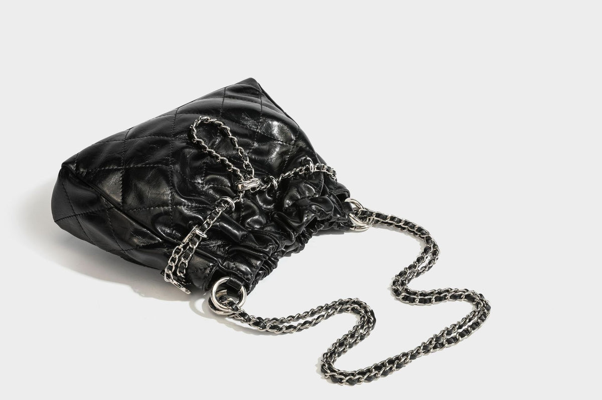 Glossy diamond-quilted drawstring bucket bag with silver chain shoulder strap and medallion charm, detail view 35