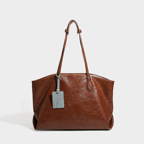 Oversized-Shopper mit lässig-weicher Form in dunkler Burgunderfarbe, glänzender geknautschter Lederoptik, zwei langen Schulterriemen und kontrastierendem
