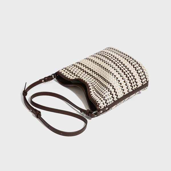 Woven stripe bucket shoulder bag in cream and dark brown with leather-look trim, knotted adjustable strap, and small shield