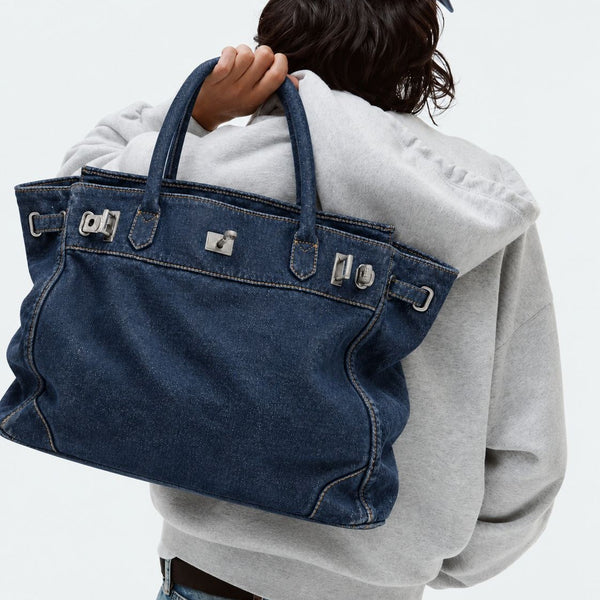 Lässig geschnittene Tote-Bag aus Denim mit silberfarbenem Drehverschluss und Schnallendetails sowie zwei gerollten Henkeln, Vorderansicht