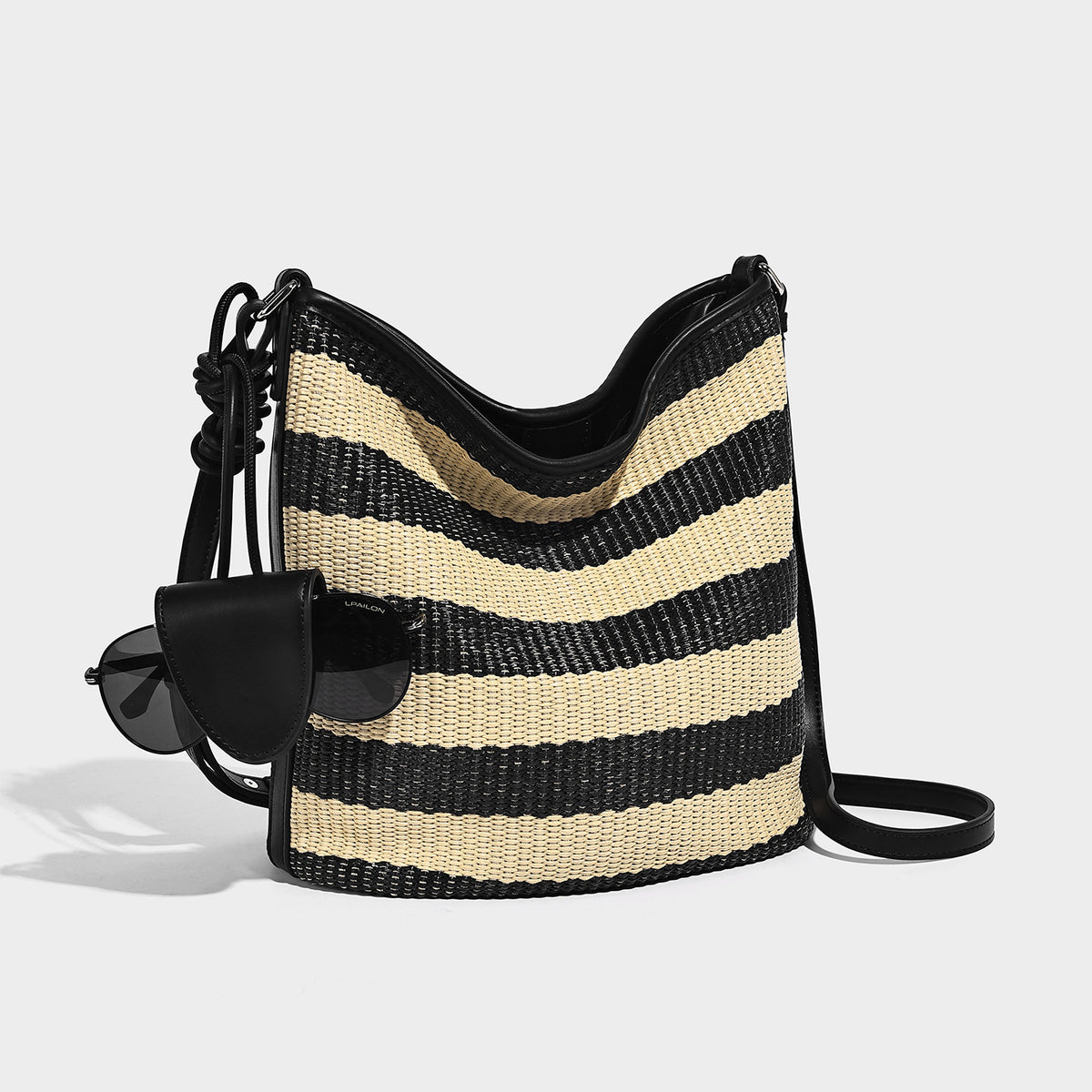 Gestreifte Webstoff-Beuteltasche in Schwarz und Beige mit schwarzem Besatz in Lederoptik, offenem oberen Rand und langem verstellbarem Schulterriemen, Detailansicht