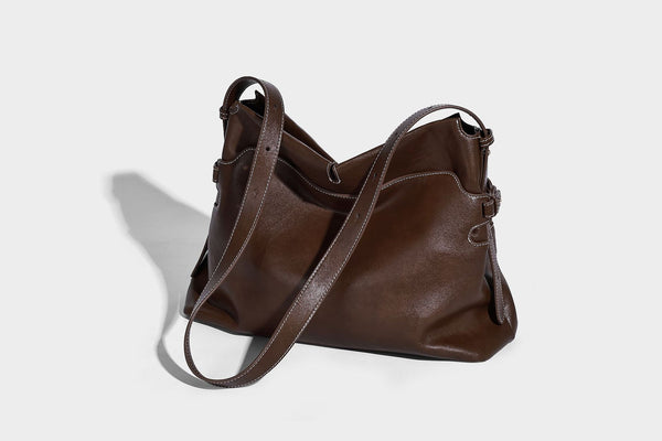 Large slouchy leather-look hobo tote bag with open top, adjustable shoulder strap, and colorful tassel bead charm, detail