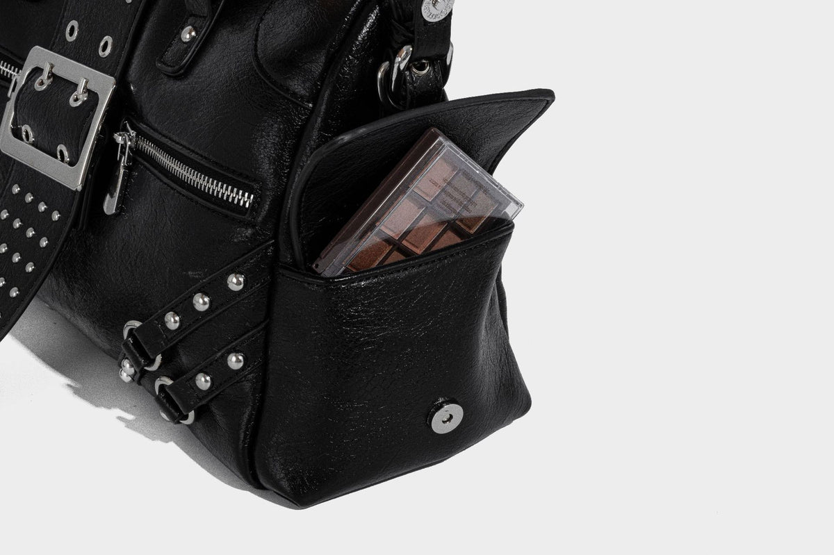 Schwarze, glänzende Henkeltasche mit genarbter Struktur, silberfarbenen Nieten, Riemendetail mit Schnalle, zwei Henkeln und breitem, mit Nieten besetztem Schulterriemen