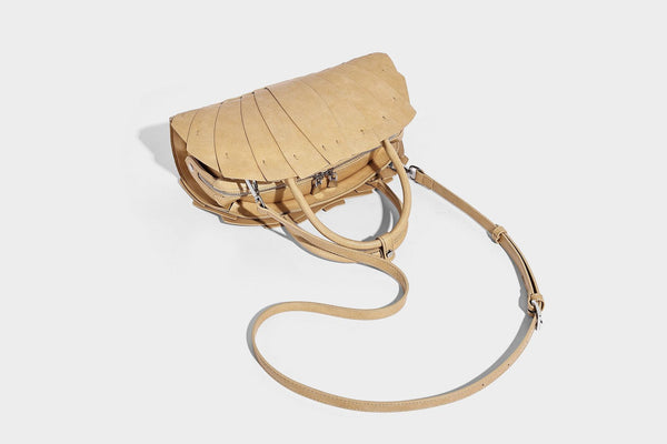 Structured dome satchel with fan-pleated leather-look exterior, dual top handles, and detachable shoulder strap, detail view