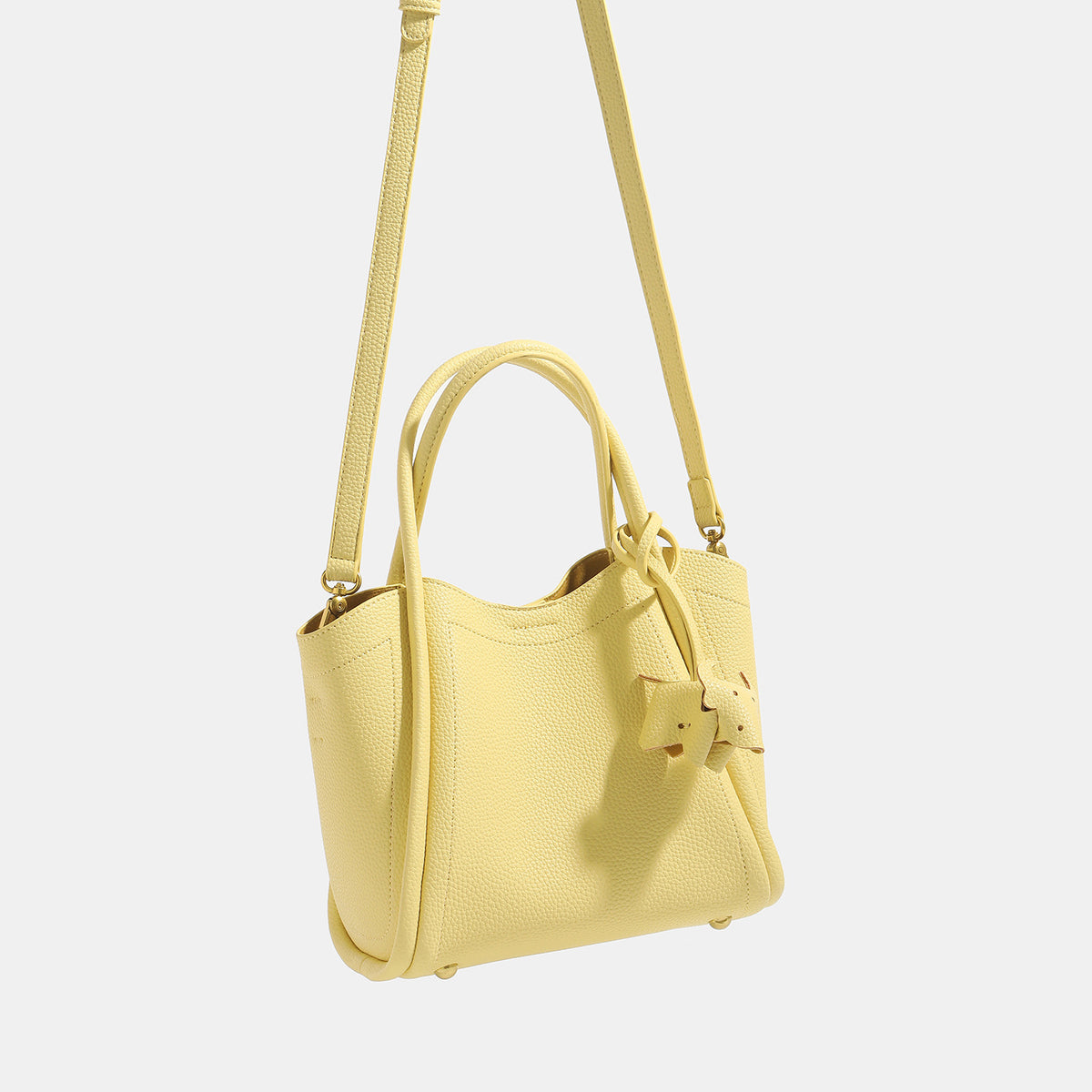 Small structured pebbled leather-look bucket tote bag with bow charm tie closure and gold-tone hardware, detail view 2