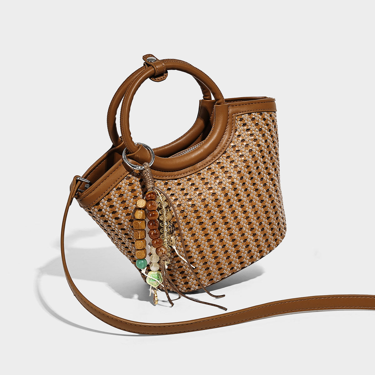 Small woven bucket bag with round leather-look ring handle, beaded tassel charm, and detachable crossbody strap in tan brown