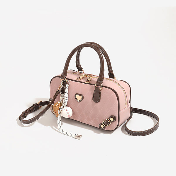 Blush pink quilted bowling barrel bag with dark brown leather-look trim and handles, baseball bat and ball charm, gold-tone