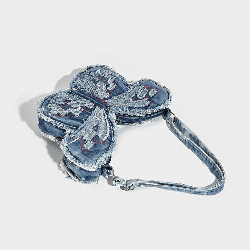 Butterfly-shaped distressed denim shoulder bag with frayed raw edges and embroidered wing panels, detail view 4