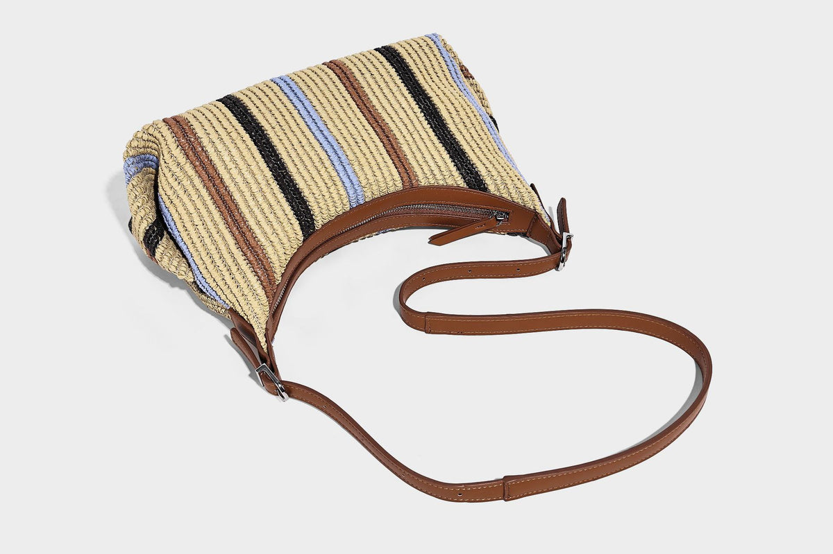 Slouchy woven straw hobo shoulder bag with beige, black, brown, and blue vertical stripes and brown leather-look trim, detail