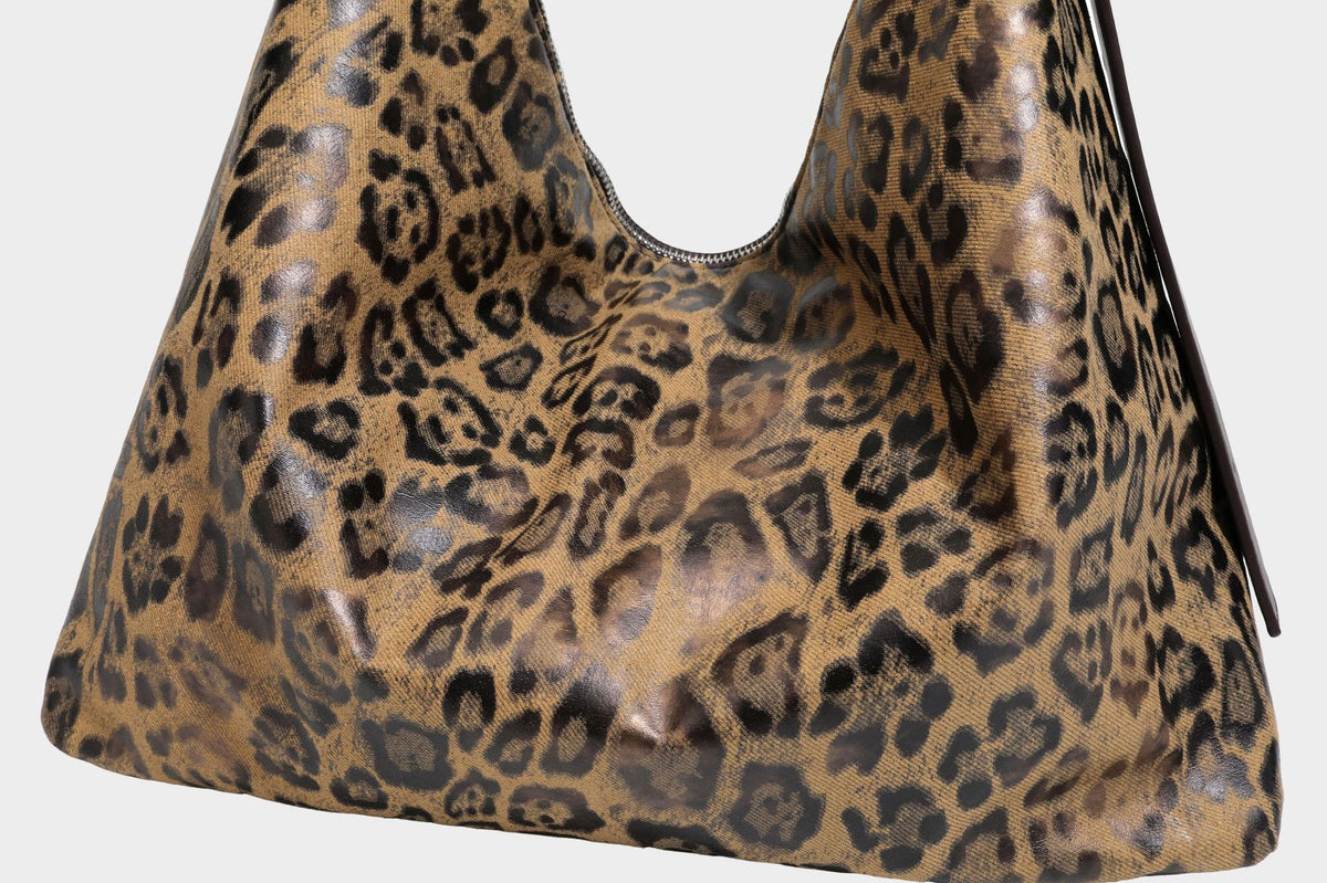 Slouchy leopard print hobo shoulder bag with glossy coated finish, top zipper closure, dark brown trim, and dangling charm
