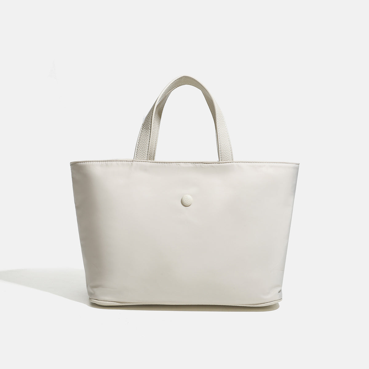 Structured lightweight nylon tote bag with textured double top handles and snap-button front detail, front view
