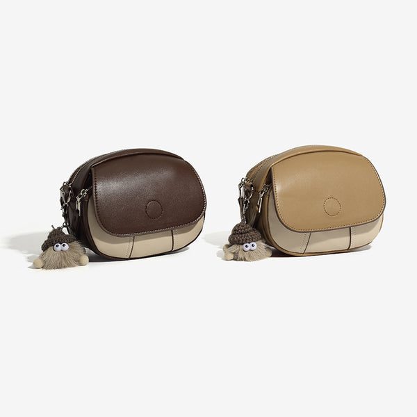 Kompakte zweifarbige ovale Umhängetasche in Lederoptik in Beige und Creme mit silberfarbenen Beschlägen und Plüsch-Anhänger, Detailansicht 2