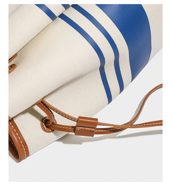 Large cream and navy striped canvas bucket tote bag with tan leather-look trim, drawstring closure, and double shoulder