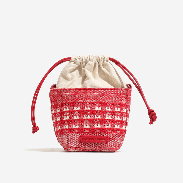 Compact openwork woven bucket bag with gathered cream drawstring liner, leather-look brown trim and cords, and gold-tone