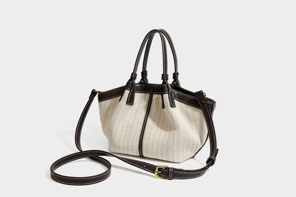 Cremefarbene geflochtene Tote-Bag mit dunkelbraunen Besätzen in Lederoptik, kontrastierenden weißen Nähten, zwei oberen Henkeln und abnehmbarem Schulter