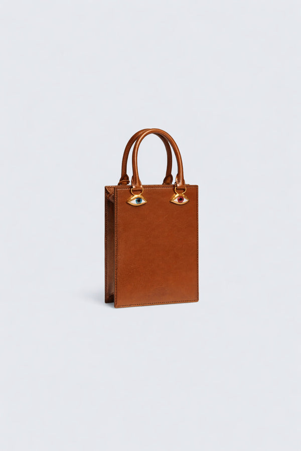 Structured rectangular top-handle bag in tan leather-look finish with gold-tone sculptural face hardware including