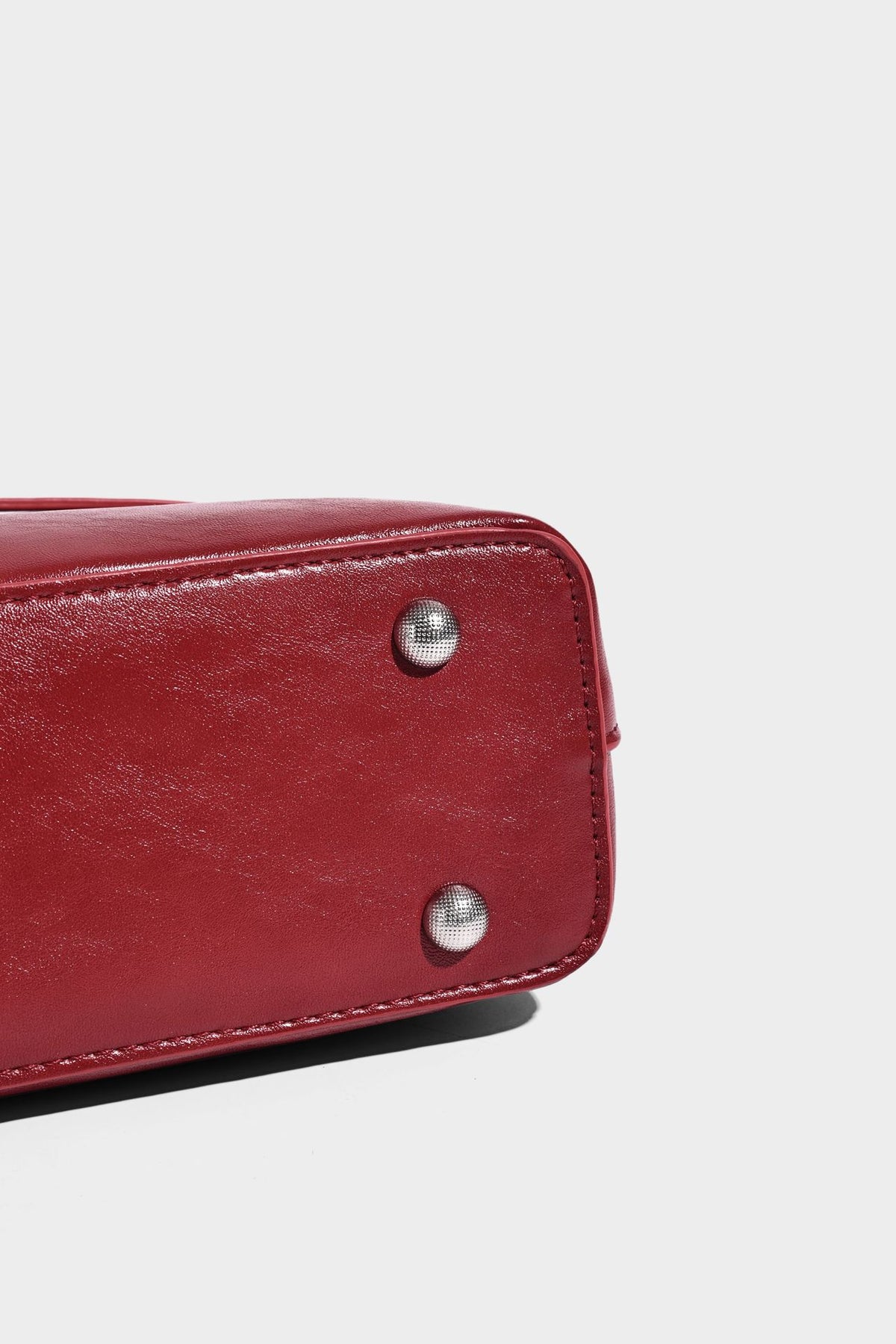 Structured glossy leather-look shoulder bag with wraparound belt straps, silver-tone hardware, and dangling star charm
