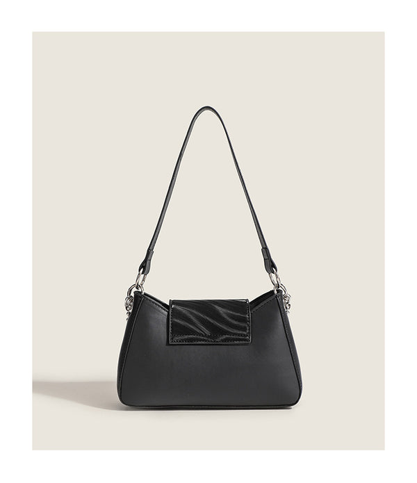 Small trapezoid shoulder bag with ripple leather-look finish, silver butterfly front clasp, and layered chain-and-ball strap