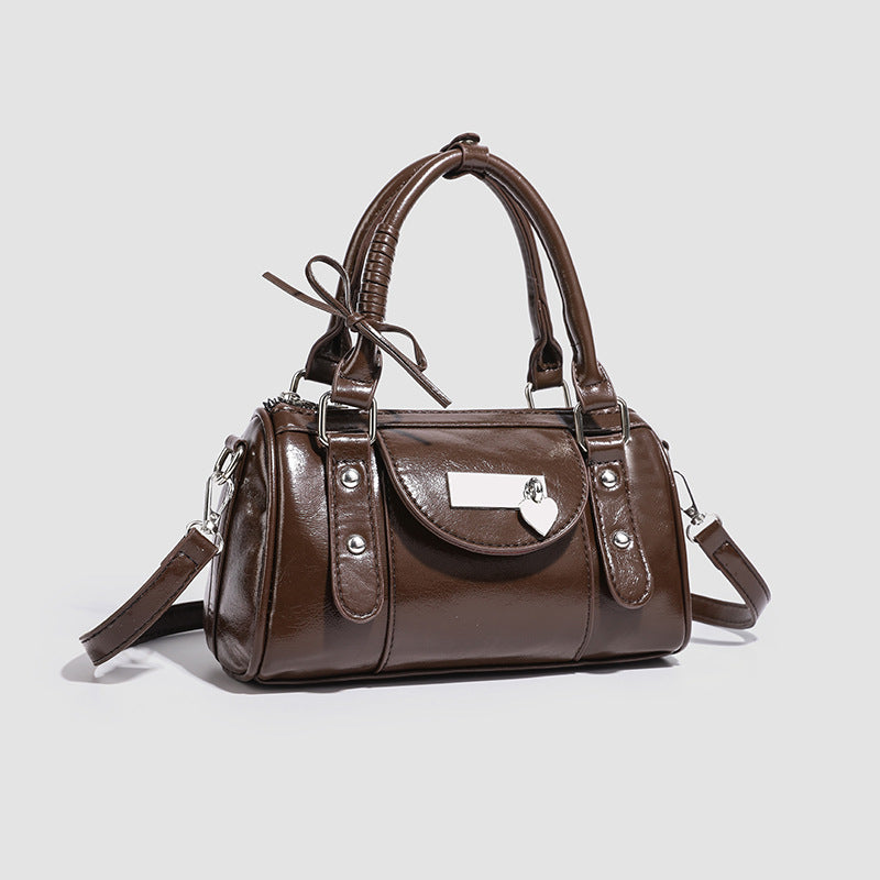 Kleine strukturierte Henkeltasche in glänzender Lederoptik mit Henkeln mit Schleifendetails und Vordertasche mit Herzverschluss, Detailansicht