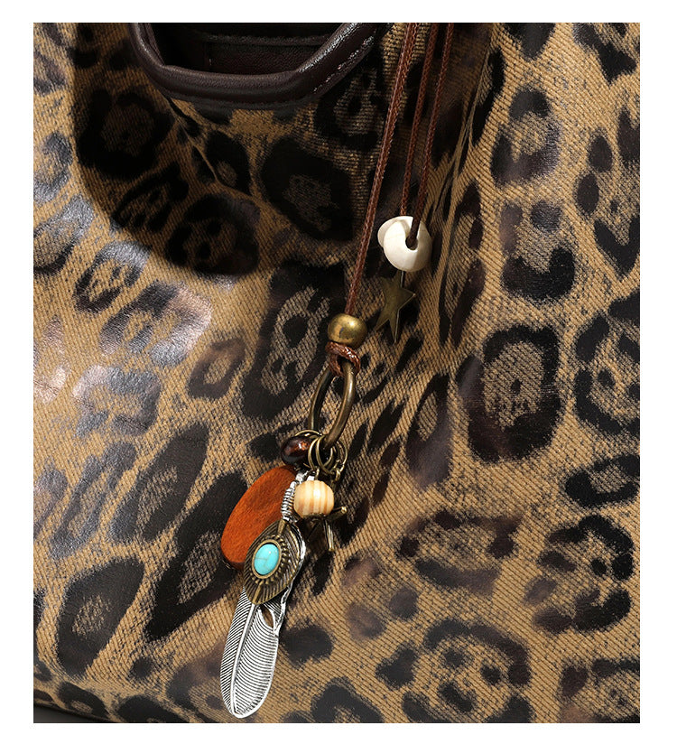 Weich fallende Hobo-Tote-Bag mit Leopardenmuster in Beige und Braun, dunkelbraunem Riemen in Lederoptik und herabhängenden Perlenanhänger-Beschlägen