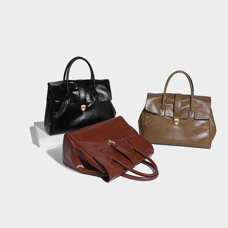 Structured glossy leather-look satchel tote with flap-over closure, center strap, gold-tone turnlock, and dual top handles